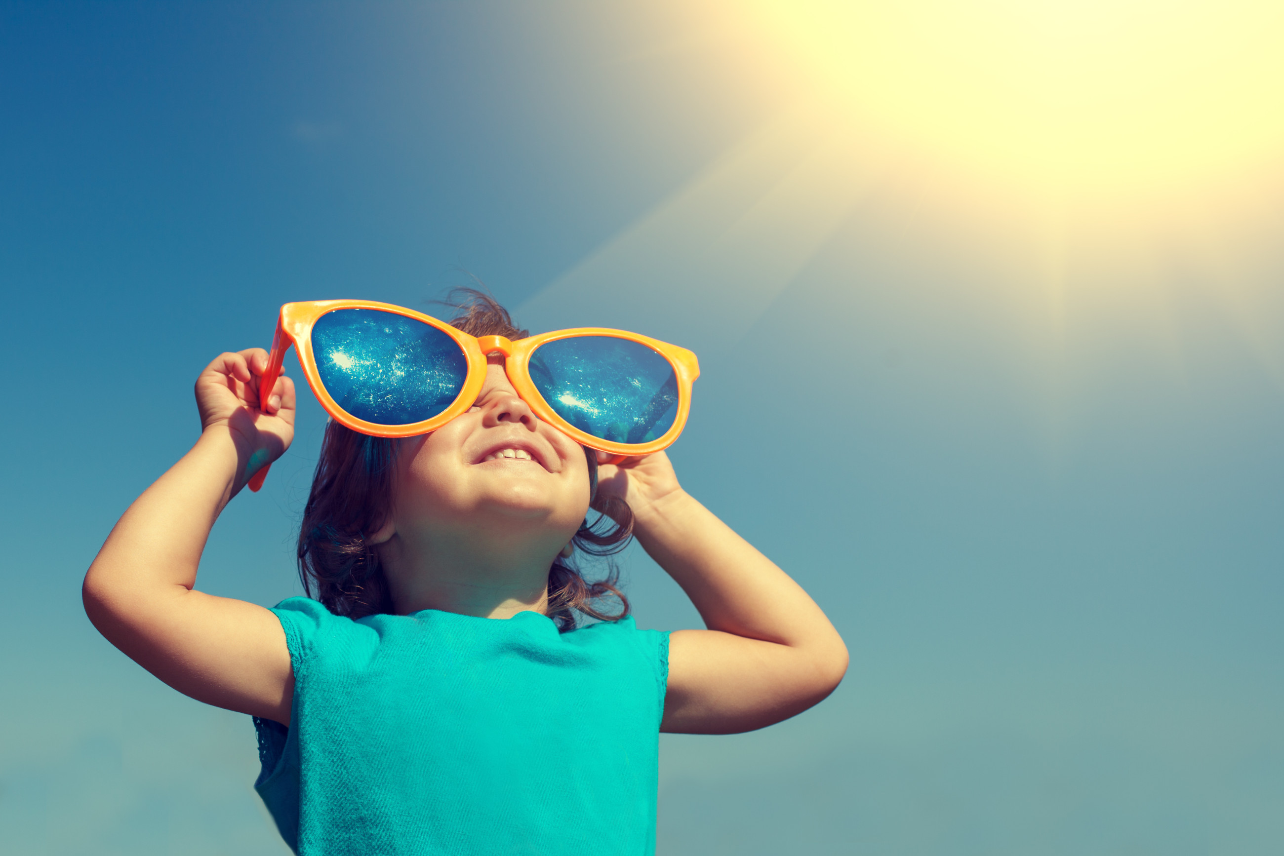 A child wearing big orange glasses on a sunny day