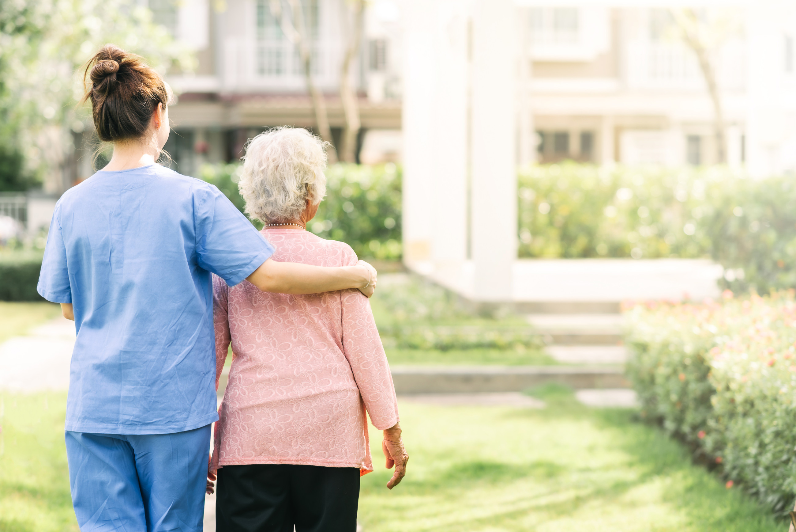 A elderly women and her care taker walking outside