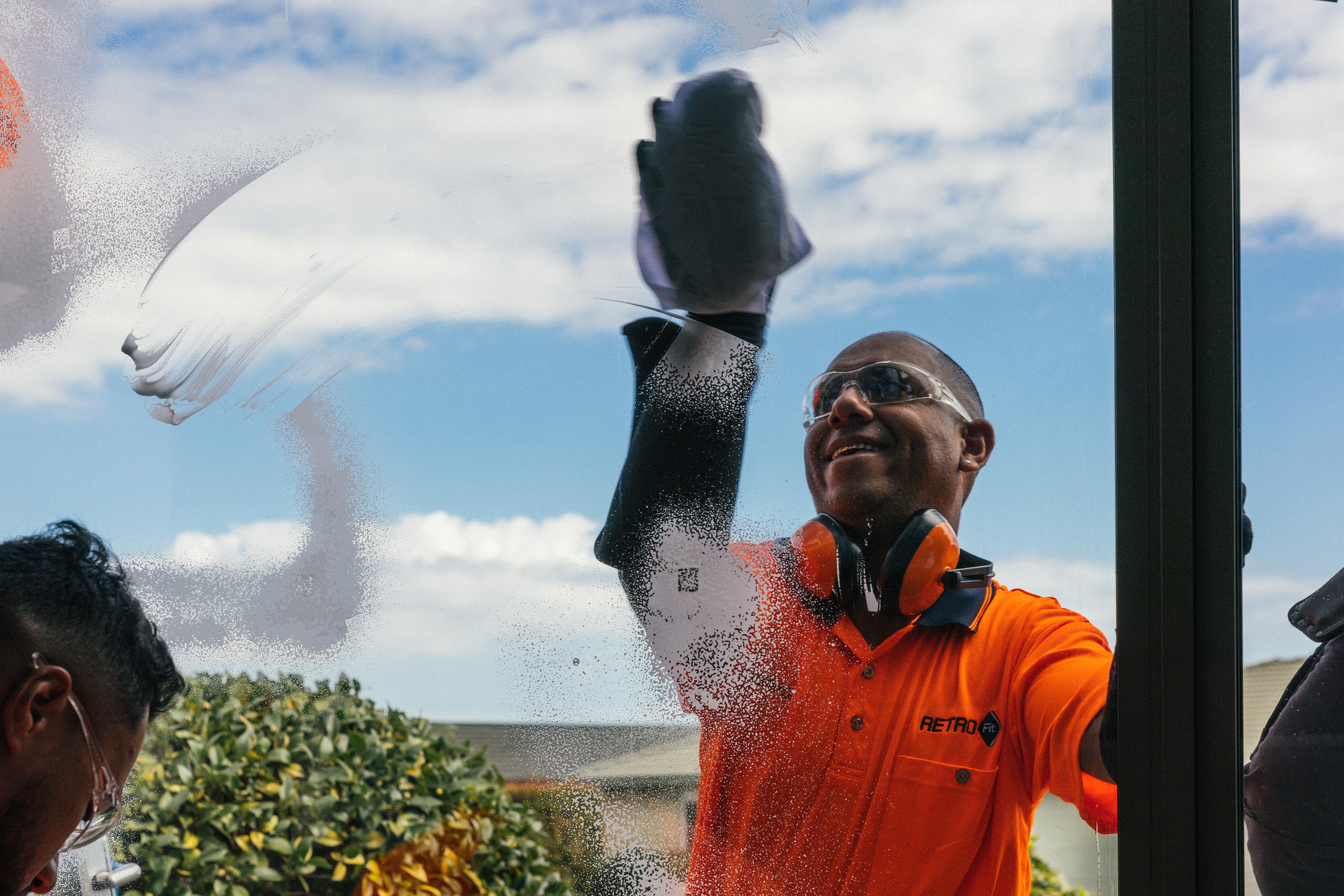 A man in orange cleaning a double glazed window