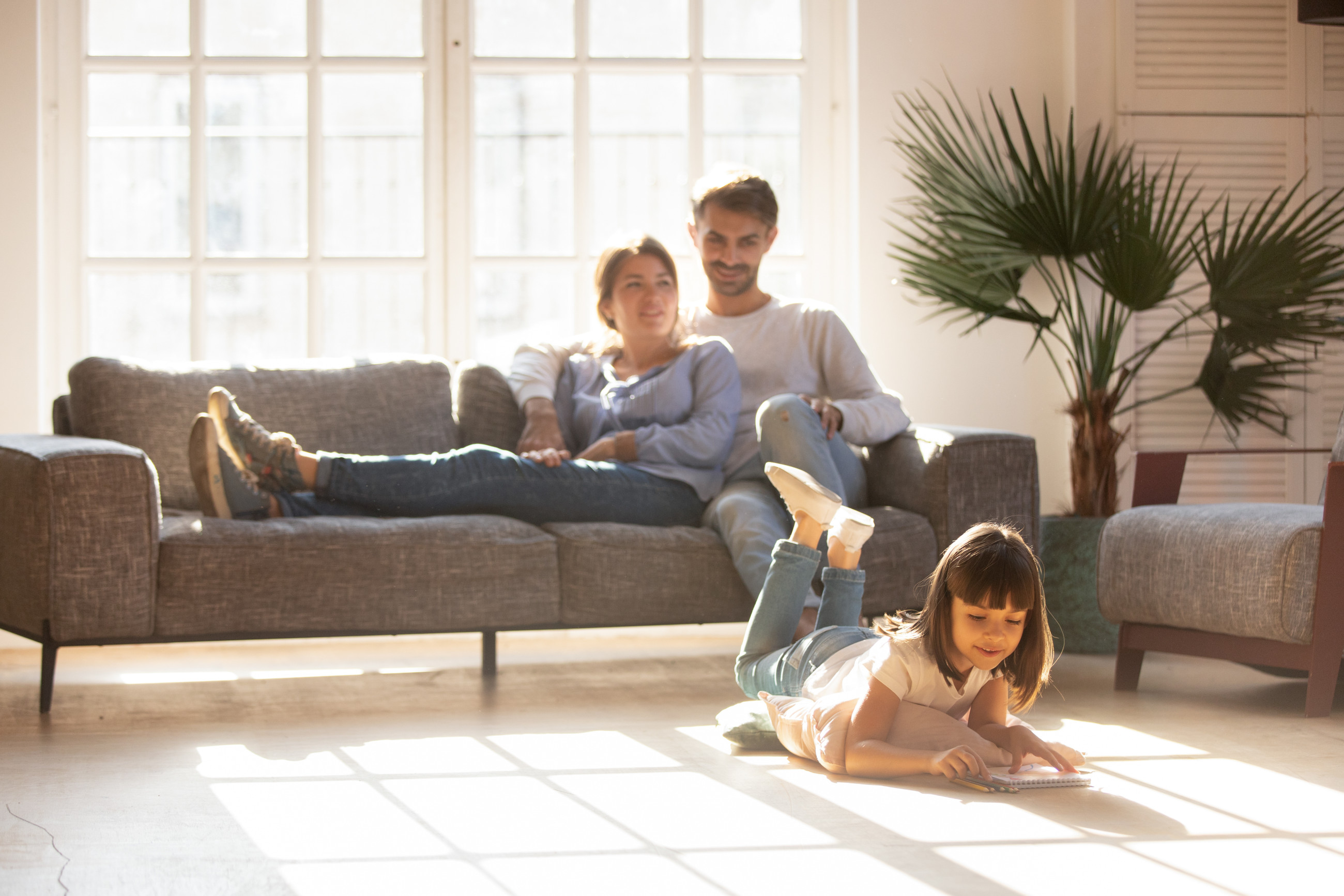 A family relaxing in their living room with the sun coming in from double glazed window