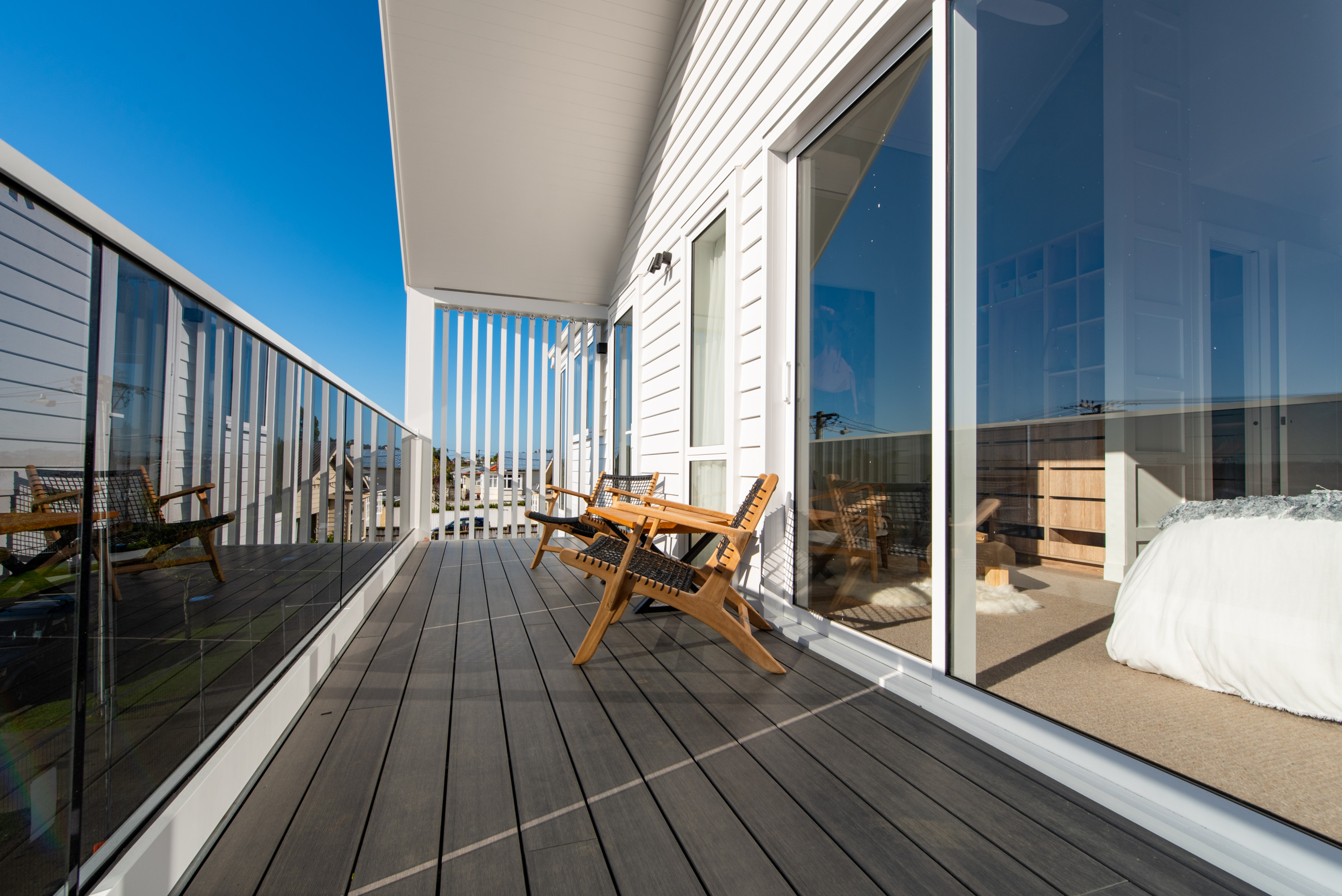 A deck with a chair in front of double glazed windows and doors.