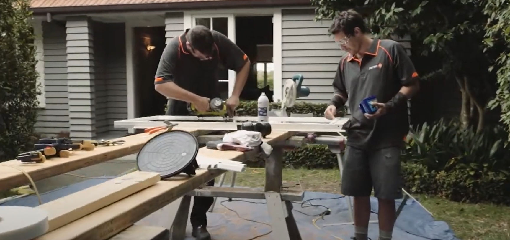 Two men cutting timber window frames to size