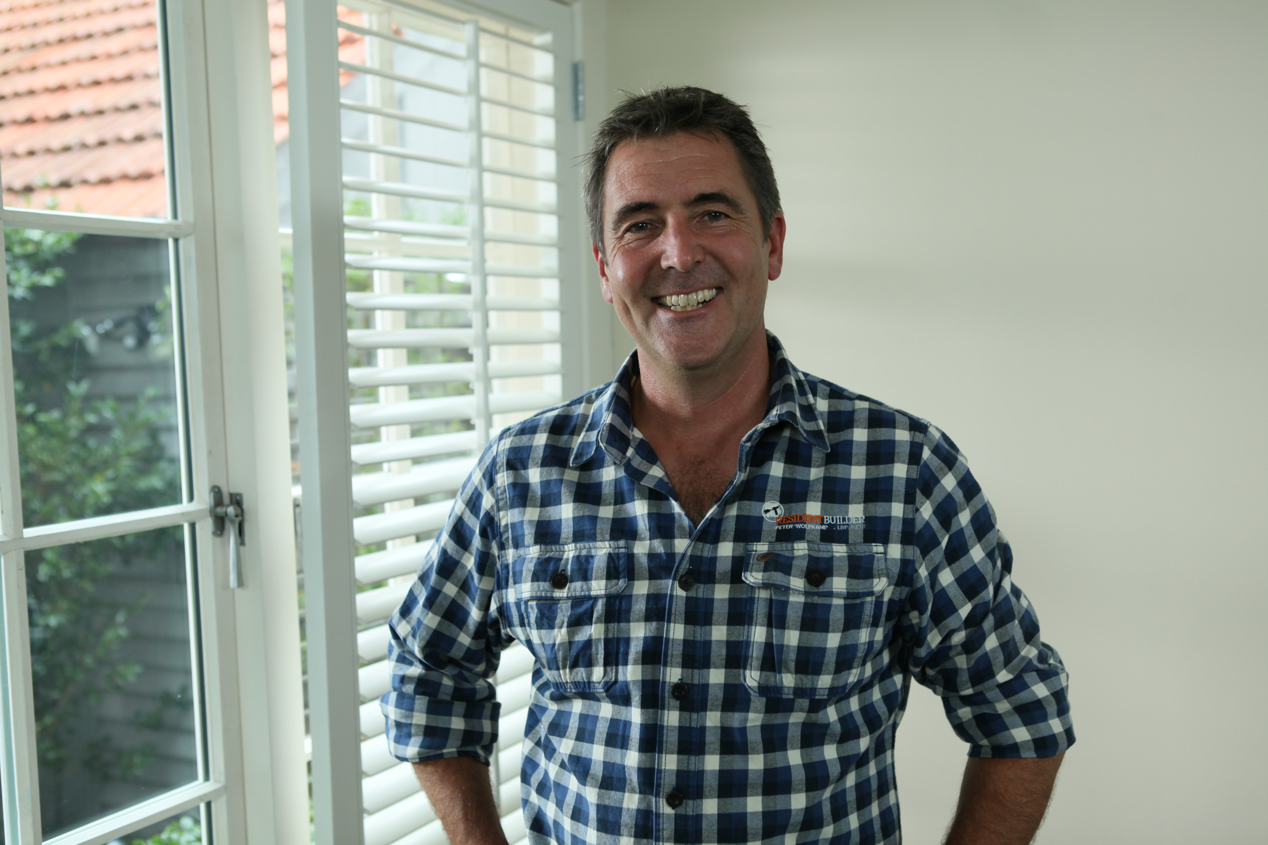 man smiling in their home in front of double glazed windows