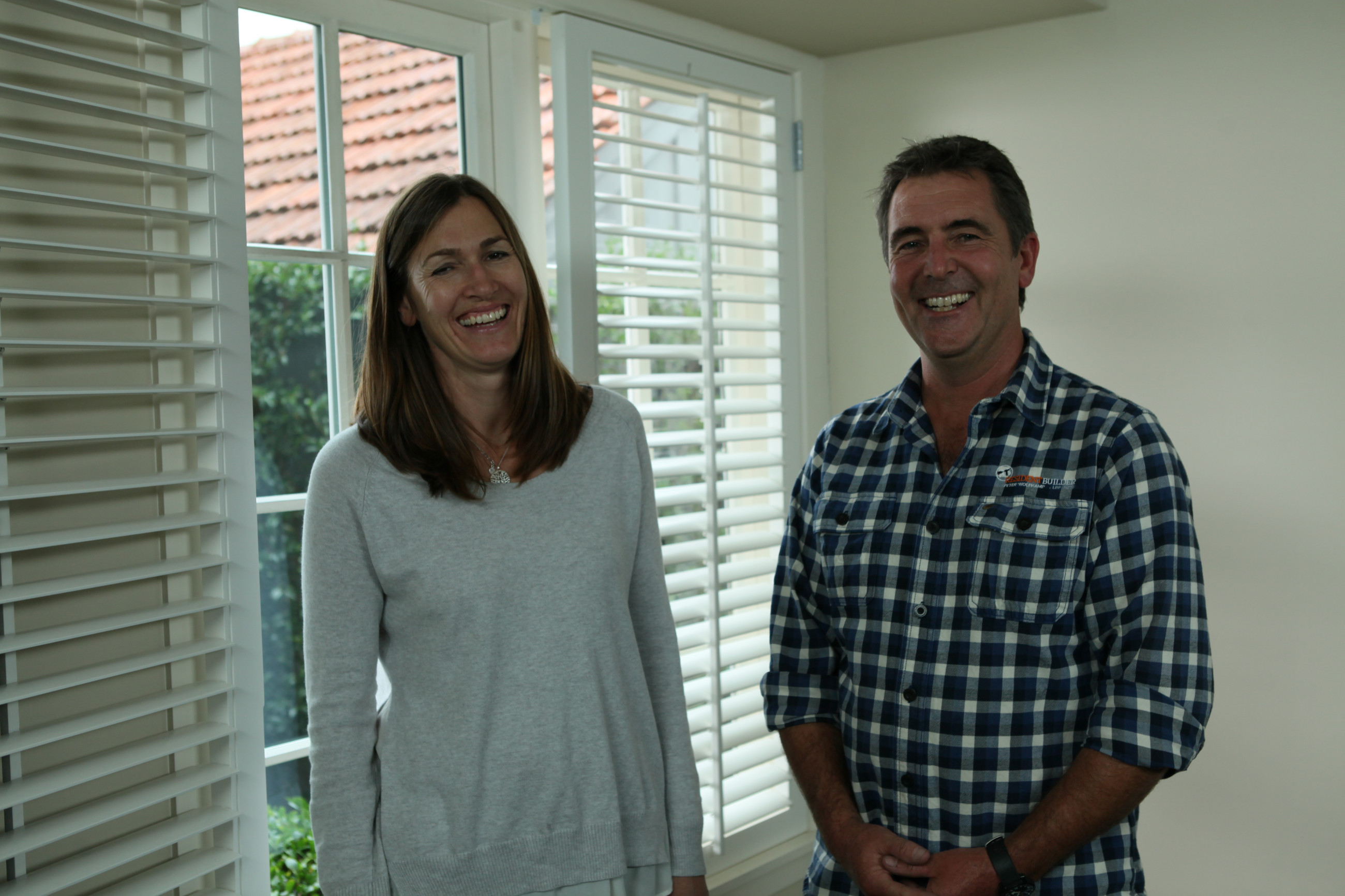 two people smiling in their home in front of double glazed windows