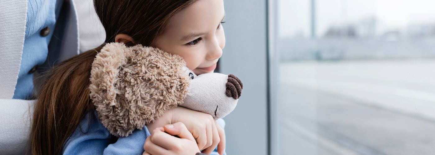 Child with teddy bear in front of double glazed windows