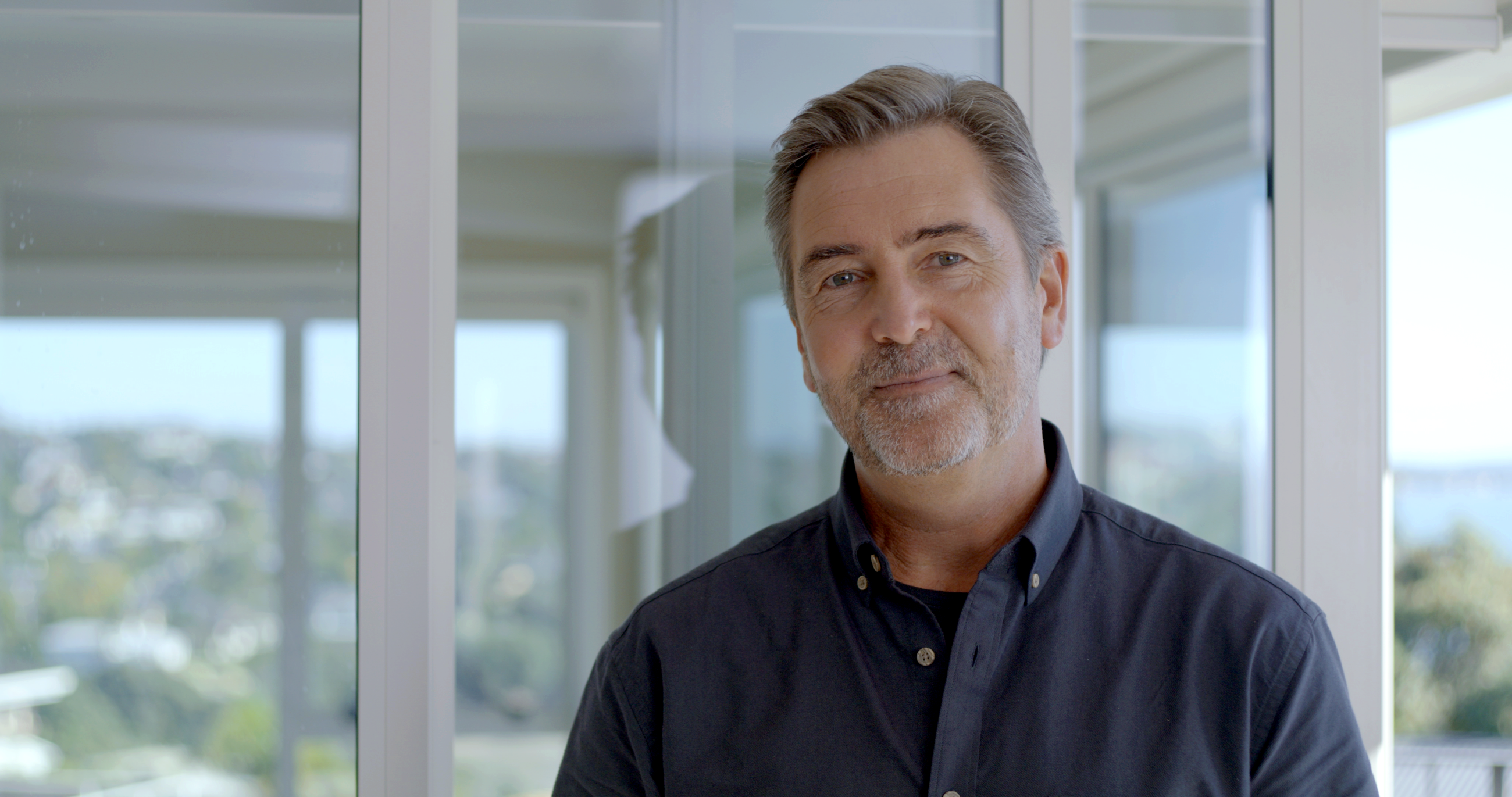 Man smiling in front of white aluminum double glazed windows